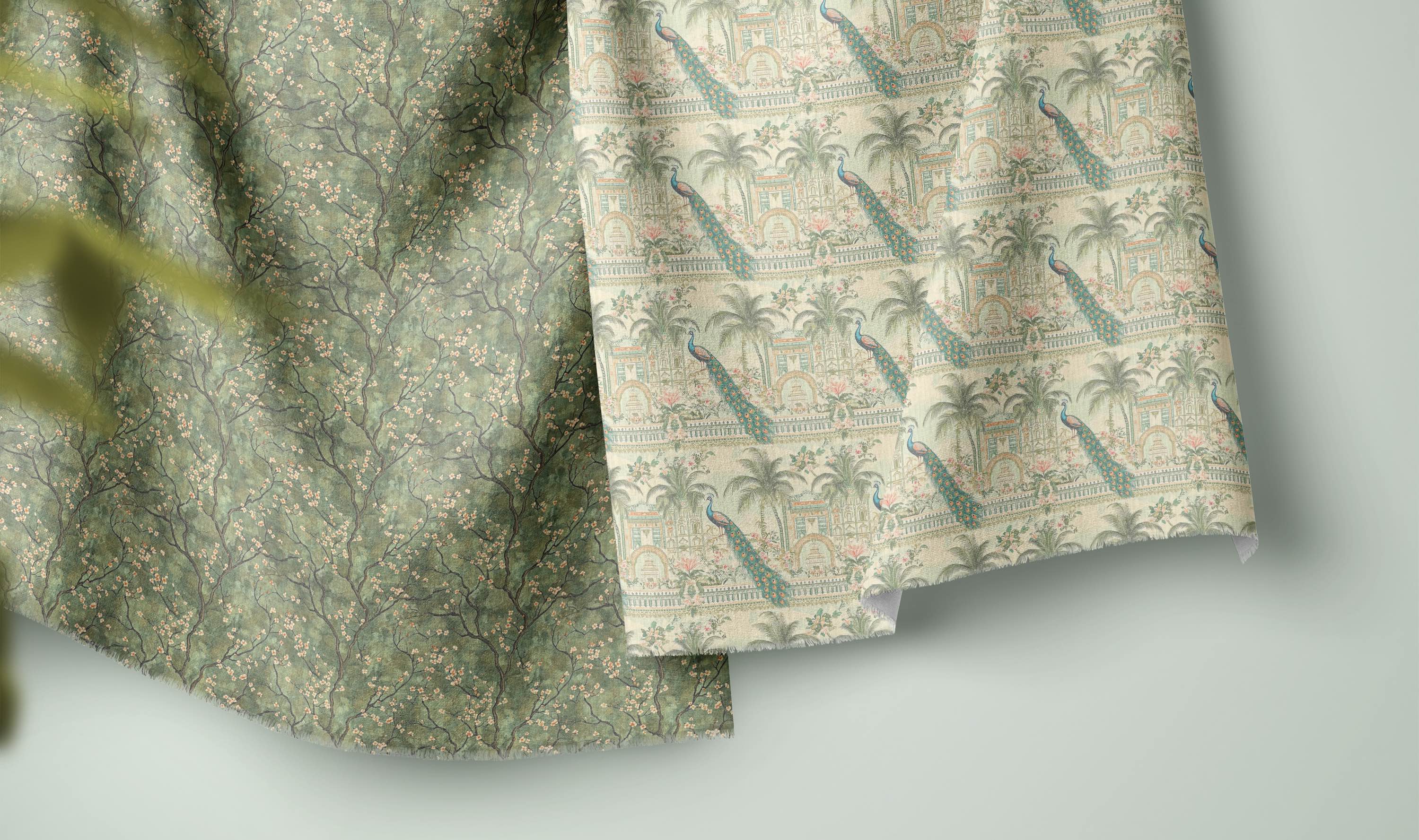 Green floral and peacock printed curtain fabrics displayed as folded linen-blend samples