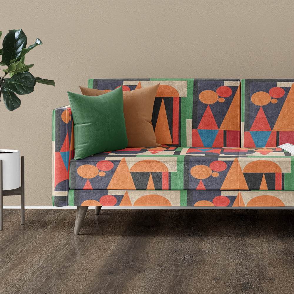 Modern sofa upholstered in bold Cubist pattern fabric in green, terracotta and coral with minimalist white and plant styling