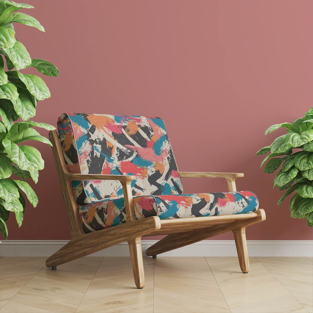 Armchair upholstered in Dash No.5 multicolour fabric – painterly brushstroke textile in modern living space with terracotta wall and wooden flooring