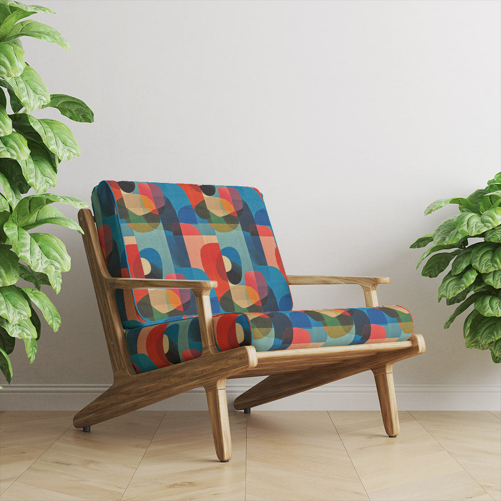 Retro wooden armchair upholstered in Dessau No.6 multicoloured upholstery fabric with bold abstract shapes in a modern interior setting.