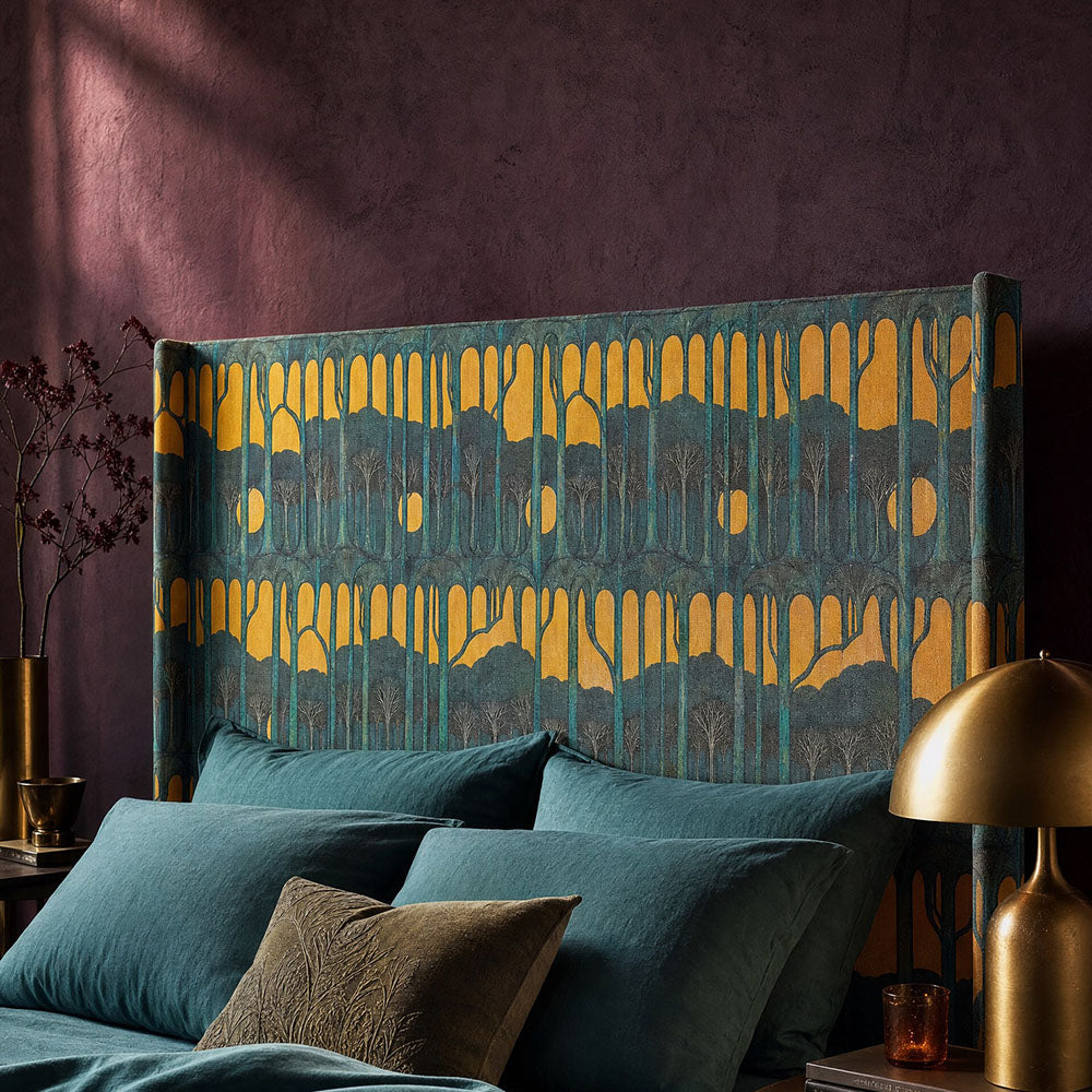 Figueres upholstery fabric featuring surreal forest silhouettes, elongated trees and abstract landscape forms in deep teal and golden ochre tones upholstered onto a statement headboard