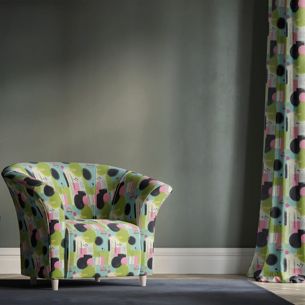 Green upholstery fabric armchair with modern abstract geometric design in green, pink and black tones in a contemporary interior