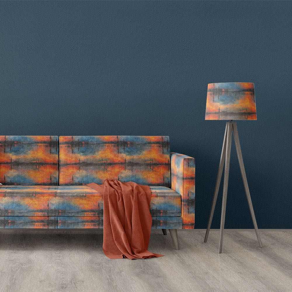 Giverny No.2 impressionist style upholstery fabric displayed on sofa and matching lampshade with atmospheric orange and blue scenic design