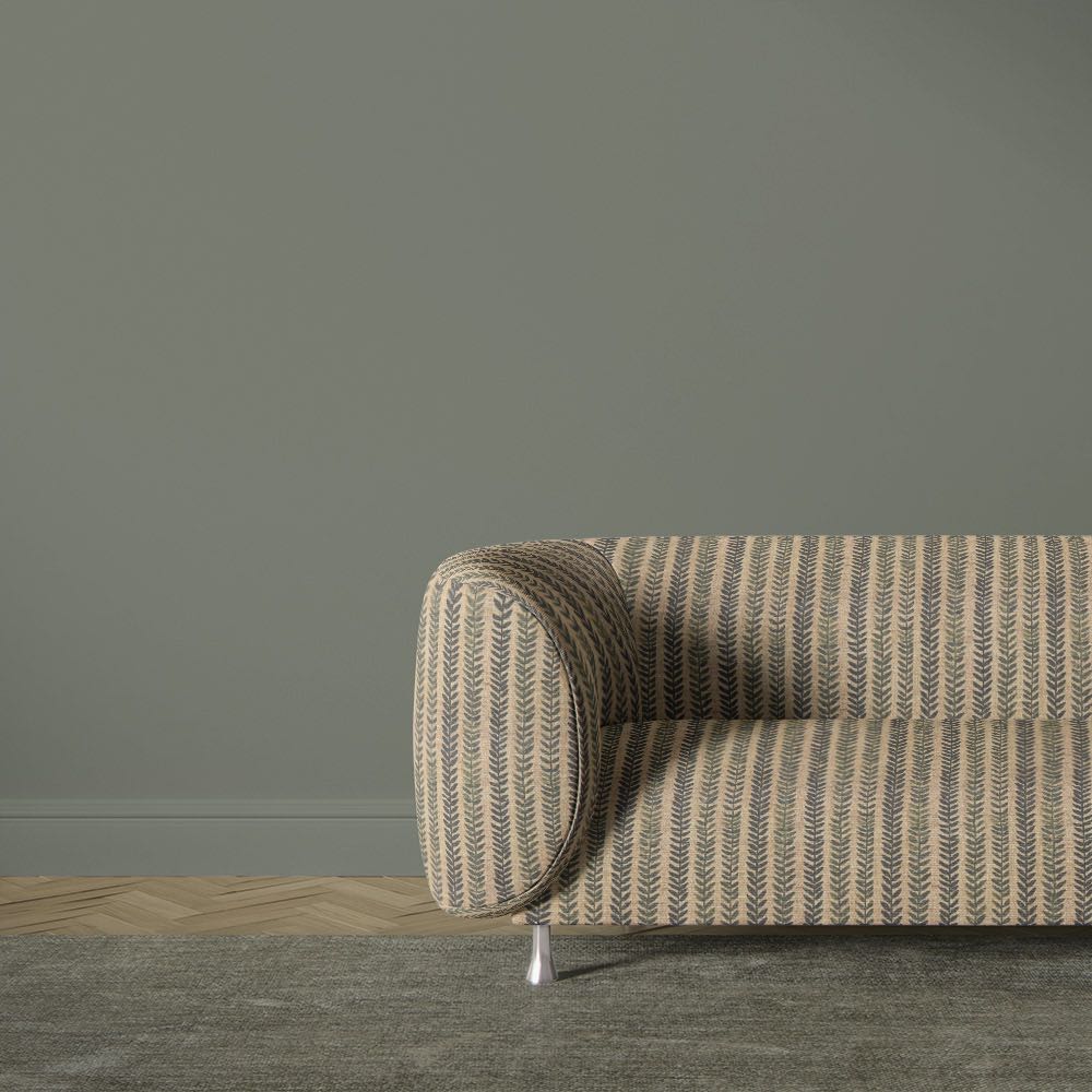 Lovverk Stripe No.11 muted green botanical stripe upholstery fabric on a curved sofa