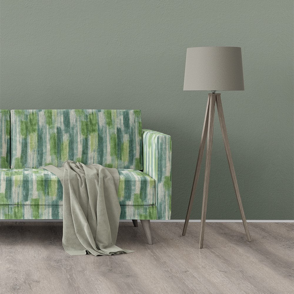 Roomset image of Striped No.27 striped upholstery fabric used on a sofa with green vertical brushstroke pattern