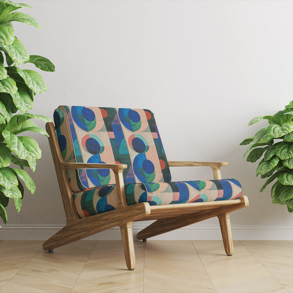 Mid-century chair upholstered in Dessau No.4 multicoloured upholstery fabric featuring Bauhaus-inspired geometric blocks and circles.