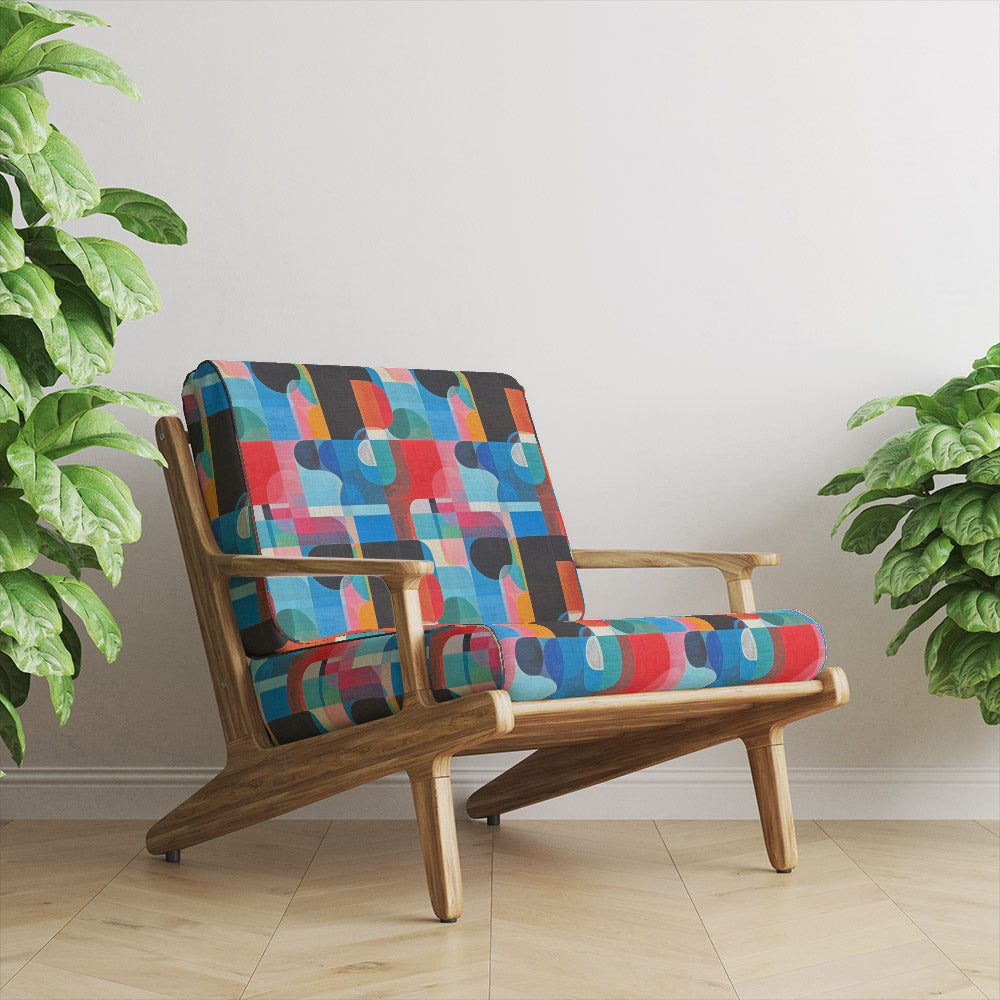 Mid-century chair upholstered in Dessau No.5 cubist multicoloured upholstery fabric in a bright, modern room