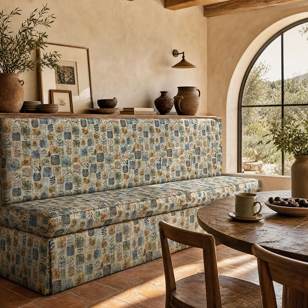 Fauve No.13 blue and green abstract upholstery fabric on an upholstered bench in a bright contemporary room