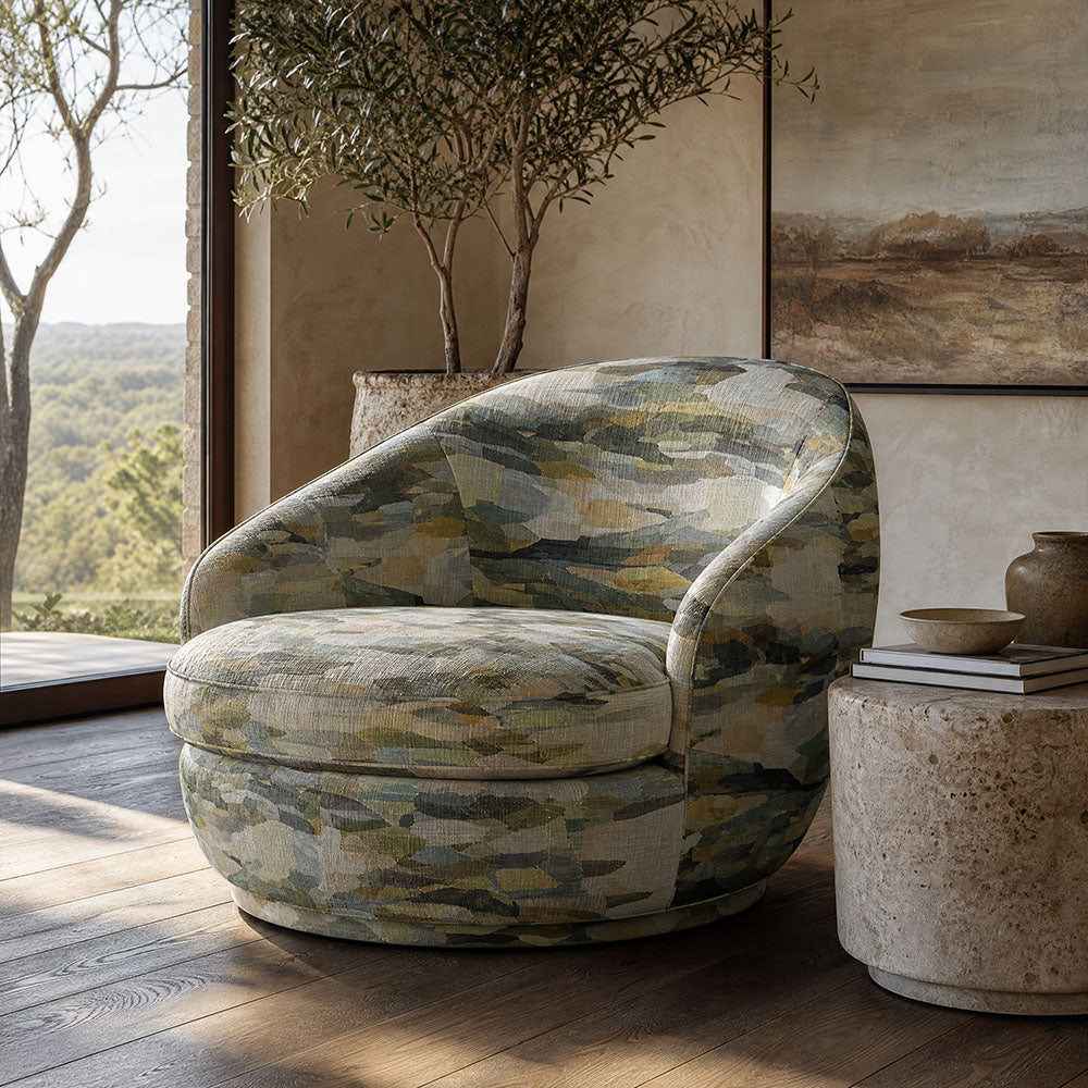 Fauve No.8 green and blue abstract upholstery fabric on a rounded statement chair in a calm contemporary room