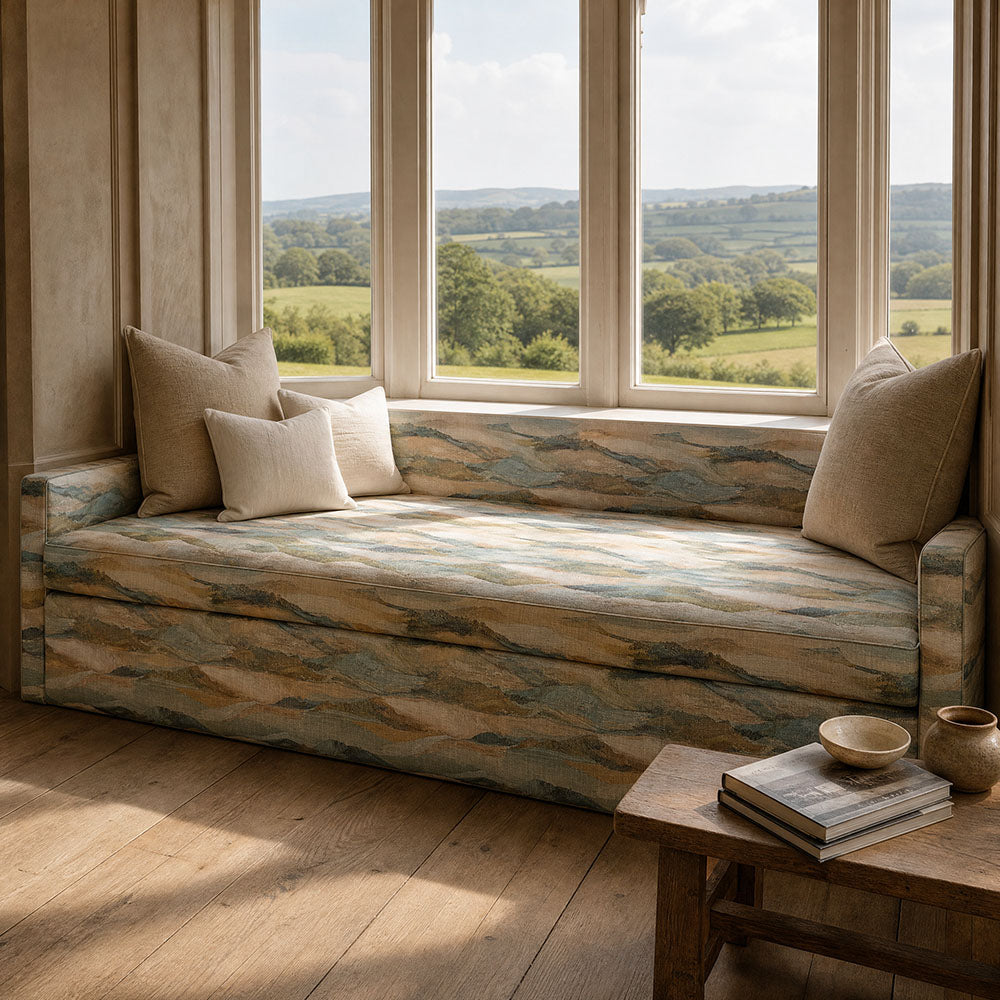 Fauve No.9 aqua blue abstract upholstery fabric on a window seat in a light relaxed interior