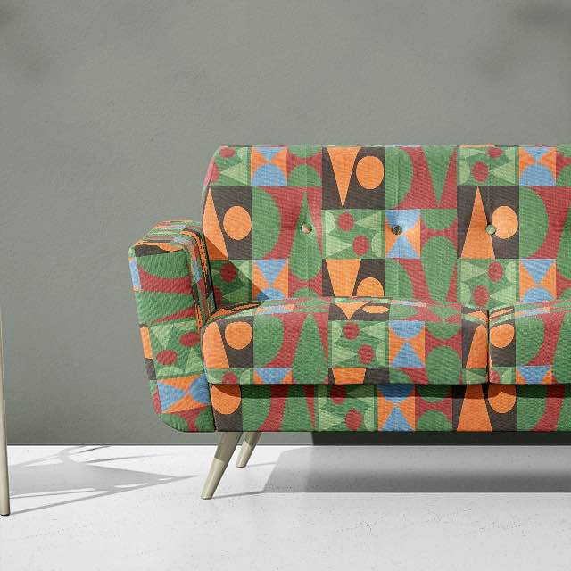 Malaga No.5 cubist fabric styled on sofa with green, orange, and blue blocks