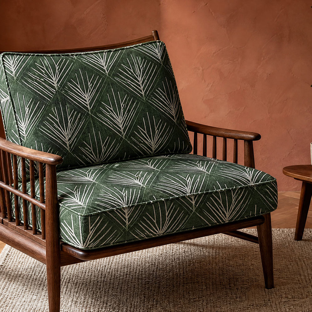 Art Nouveau upholstery fabric featuring elegant botanical leaf motifs arranged in a flowing geometric pattern in deep green and ivory tones upholstered onto a contemporary armchair