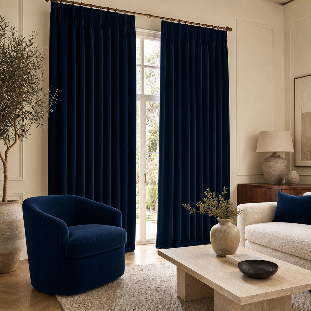Portafino Midnight velvet curtain and upholstery fabric featuring rich navy blue velvet curtains with a matching upholstered accent chair in a bright contemporary living room