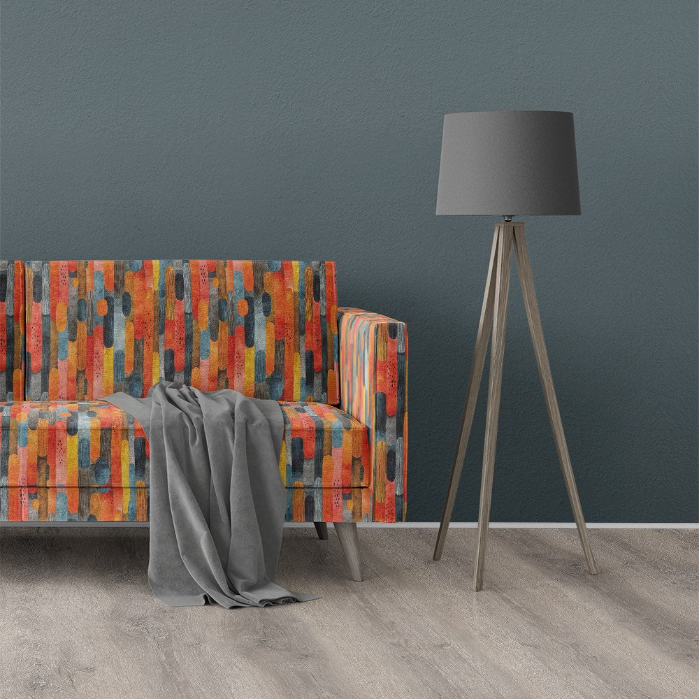 Sofa upholstered in Striped No.20 multicoloured striped upholstery fabric styled with dark grey lamp and slate blue wall.