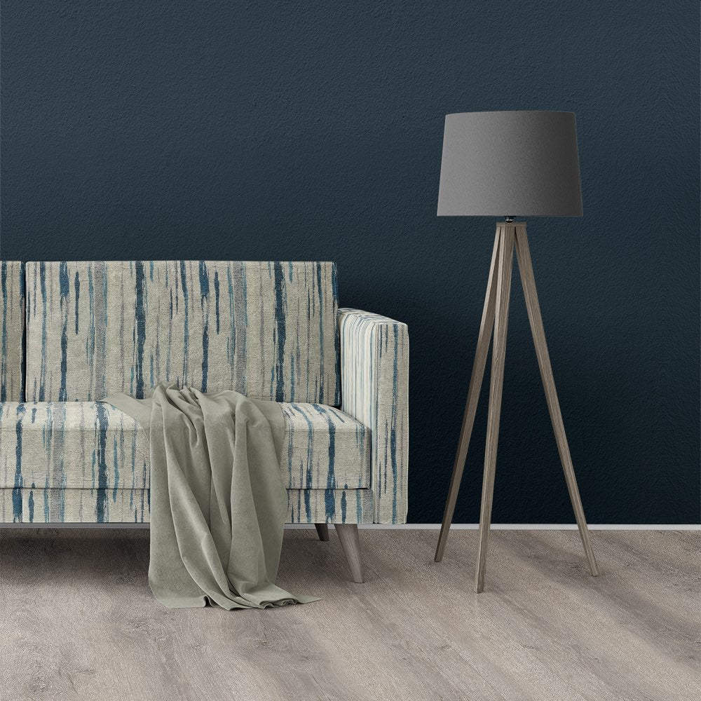 Roomset with sofa upholstered in Striped No.22 blue striped upholstery fabric, styled against a navy wall with wood flooring