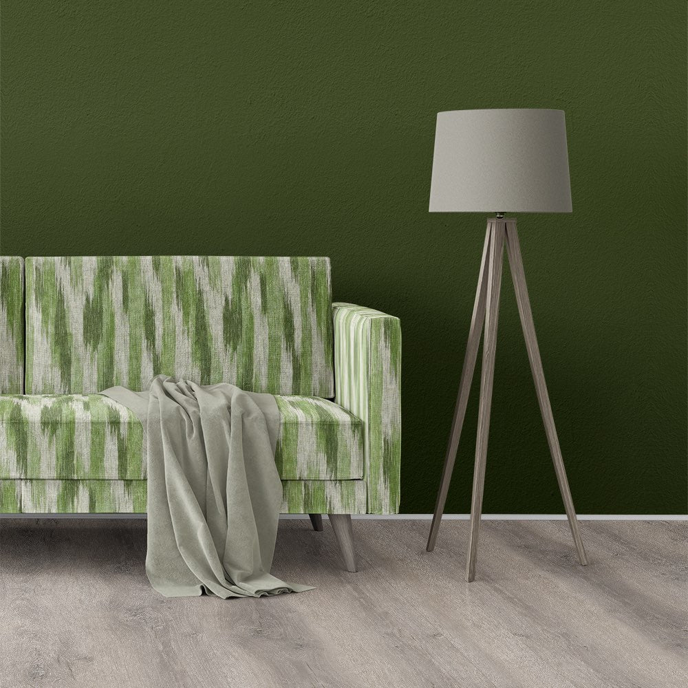Striped No.28 green striped upholstery fabric styled on a modern boxy sofa against olive wall